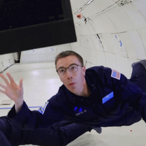 A Man In A Zero G Space Suit Is Floating In The Air GIF