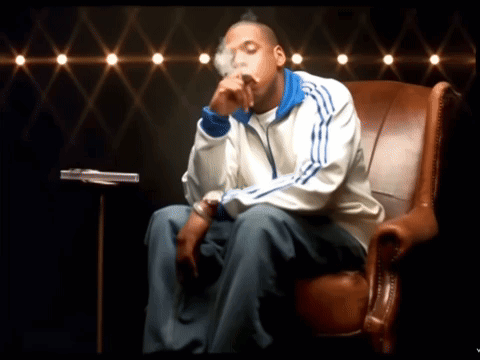 A Man In An Adidas Jacket Sits In A Chair GIF