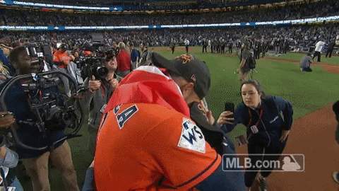 A Man In An Astros Jersey Is Hugging Another Man On A Baseball Field GIF