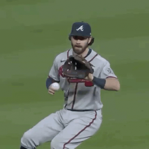 A Man In An Atlanta Braves Jersey Is Standing On A Baseball Field And Smiling . GIF