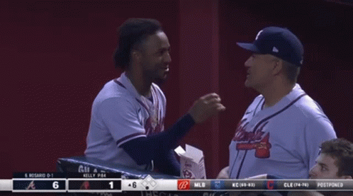 A Man In An Atlanta Braves Jersey Talks To Another Man In A Baseball Dugout GIF