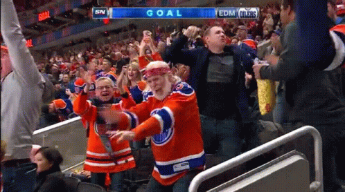 A Man In An Edmonton Oilers Jersey Is Dancing In The Stands At A Hockey Game GIF