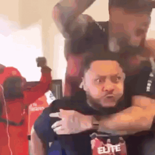 A Man In An Elite Shirt Is Carrying Another Man On His Shoulders GIF
