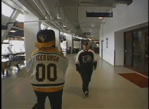 A Man In An Iceburgh Jersey Walks Down A Hallway Next To Another Man GIF