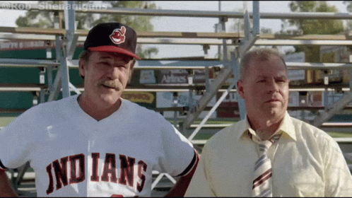 A Man In An Indians Jersey Stands Next To Another Man In A Tie GIF