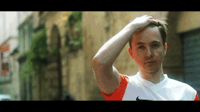 Man In Orange And White Nike Shirt Holding Hand To Forehead GIF