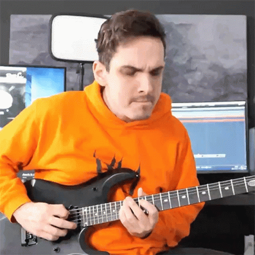 A Man In An Orange Hoodie Playing A Guitar GIF