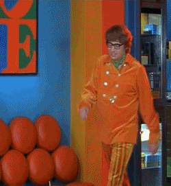 A Man In An Orange Jacket And Striped Pants Is Dancing GIF