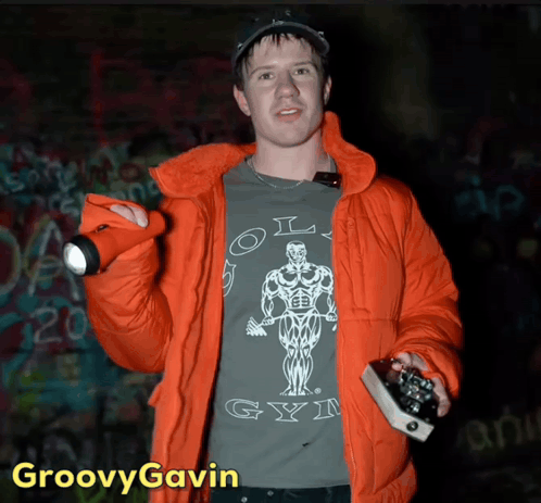 A Man In An Orange Jacket Is Wearing A Shirt That Says Old Gym On It GIF