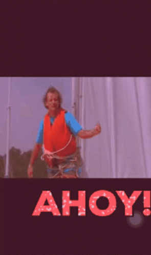 A Man In An Orange Life Vest Is Standing In Front Of A Sign That Says Ahoy ! GIF