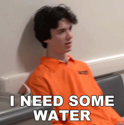 A Man In An Orange Prison Uniform Is Sitting In A Chair And Says I Need Some Water GIF