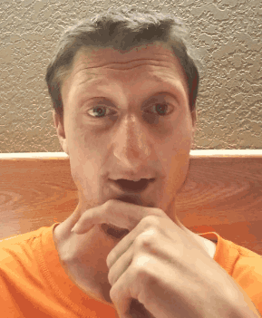 A Man In An Orange Shirt Is Making A Face GIF
