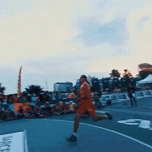 A Man In An Orange Shirt Is Running On A Track With The Number 3 On It GIF