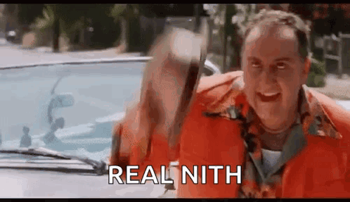 A Man In An Orange Shirt Is Standing Next To A Car And Holding A Hammer . GIF