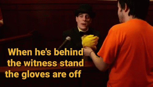 A Man In An Orange Shirt Is Talking To A Man In A Top Hat Behind A Witness Stand GIF