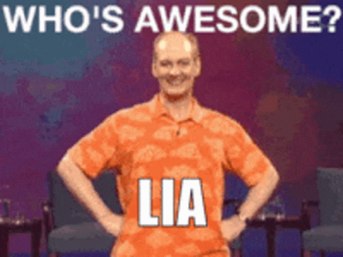 A Man In An Orange Shirt Stands With His Hands On His Hips In Front Of A Sign That Says " Who 'S Awesome Lia " GIF