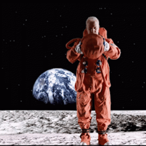 A Man In An Orange Space Suit Stands On The Moon In Front Of The Earth GIF