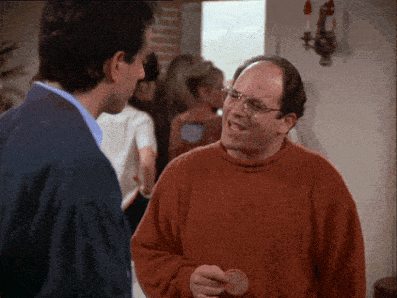 A Man In An Orange Sweater Is Talking To Another Man In A Blue Jacket GIF