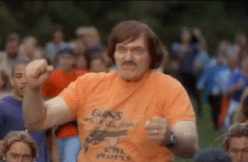 A Man In An Orange T-Shirt With A Gun On It Is Dancing In Front Of A Crowd . GIF