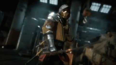 A Man In Armor Is Holding A Sword In His Hand In A Room . GIF