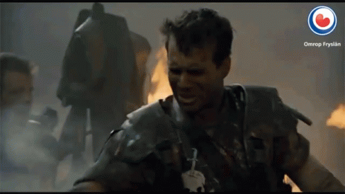 A Man In Armor Is Smiling In Front Of A Fire And A Sign That Says Omrop Frysian GIF