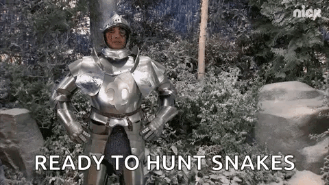 A Man In Armor Is Standing In A Snowy Forest With His Hands On His Hips . GIF