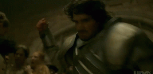 A Man In Armor Is Standing In Front Of A Group Of People In A Dark Room . GIF