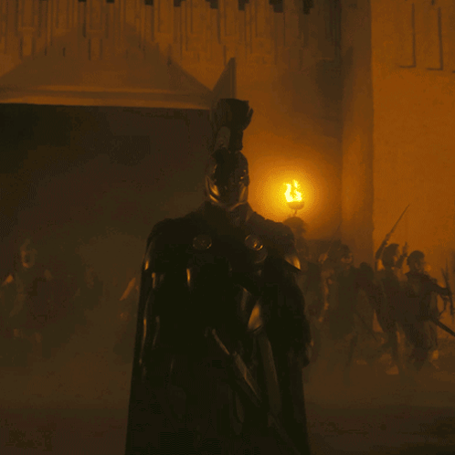 A Man In Armor Is Standing In Front Of A Wall With The Letter J Written On It GIF