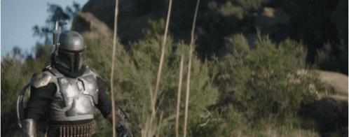 A Man In Armor Is Standing In The Middle Of A Field With Trees In The Background . GIF