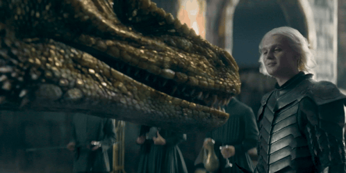 A Man In Armor Is Standing Next To A Dragon GIF