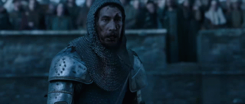 A Man In Armor Stands In Front Of A Crowd Of People GIF