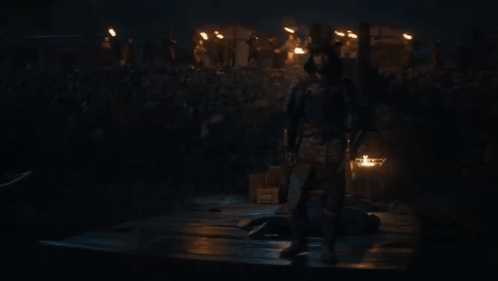 a man in armor stands in front of a crowd of people holding a sword