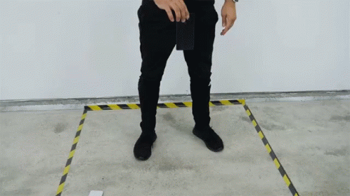 A Man In Black Pants Is Standing In A Yellow And Black Line GIF