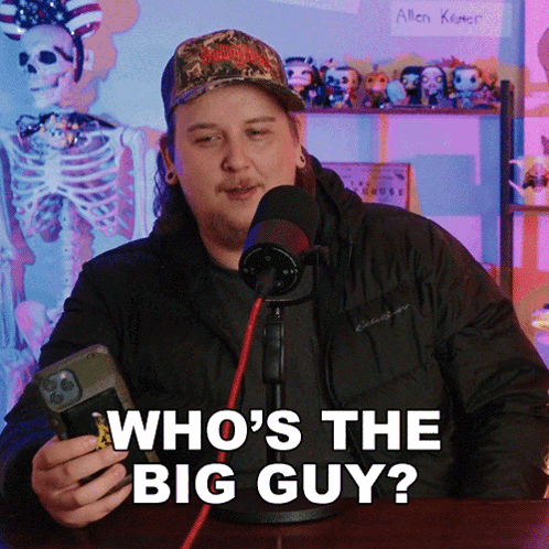 A Man In Front Of A Microphone Is Holding A Cell Phone And Says Who 'S The Big Guy GIF