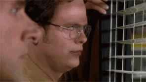 A Man In Glasses Is Looking Out Of A Window . GIF
