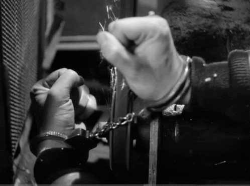 A Man In Handcuffs Is Trying To Unlock A Door GIF