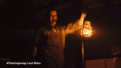 A Man In Overalls Is Holding A Lantern In A Dark Room GIF