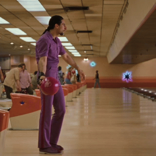 A Man In Purple Pants Holds A Red Bowling Ball With A Star On It GIF