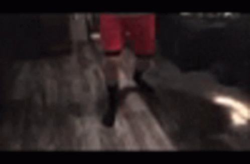 A Man In Red Shorts Is Standing In A Kitchen With His Arms Around His Chest . GIF