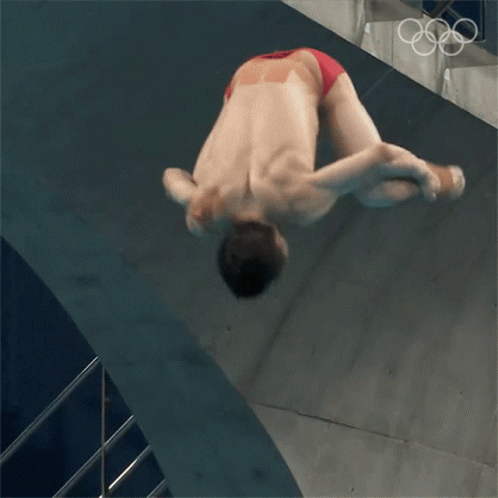 A Man In Red Swim Trunks Is Diving Into A Pool GIF