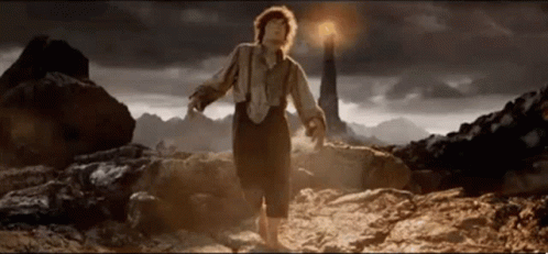 A Man In Suspenders Is Standing In Front Of A Lighthouse In The Desert . GIF