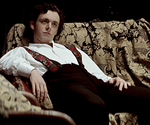 Man In Suspenders Sitting On Couch GIF