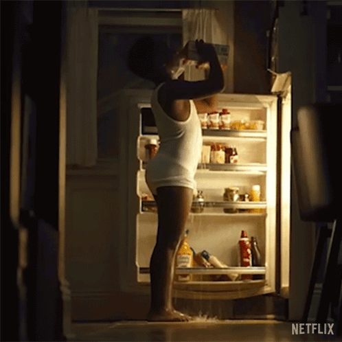 A Man In Underwear Is Standing In Front Of An Open Refrigerator At Night . GIF