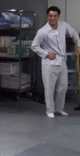 A Man In White Pajamas Stands In A Room GIF