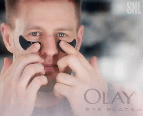 A Man Is Applying Black Eye Patches From Olay Eye Black GIF