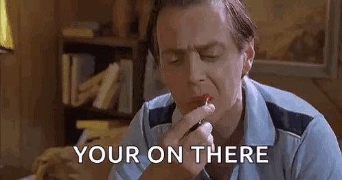 A Man Is Applying Lipstick To His Lips While Sitting At A Table . GIF