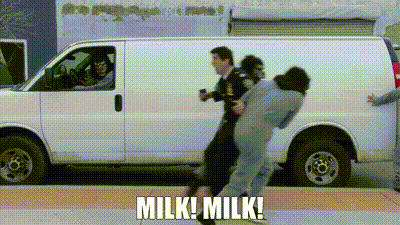 A Man Is Being Held By A Police Officer In Front Of A Van . GIF