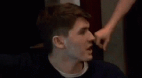 A Man Is Being Punched In The Face By Another Man While Sitting Down . GIF