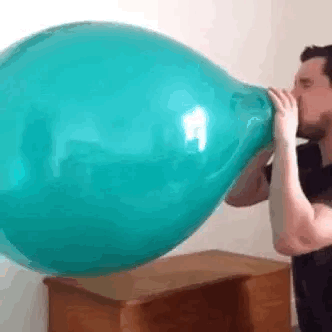 A Man Is Blowing Up A Blue Balloon On A Table . GIF