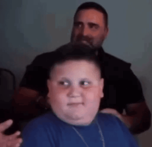 A Man Is Brushing A Boy 'S Hair In A Room . GIF